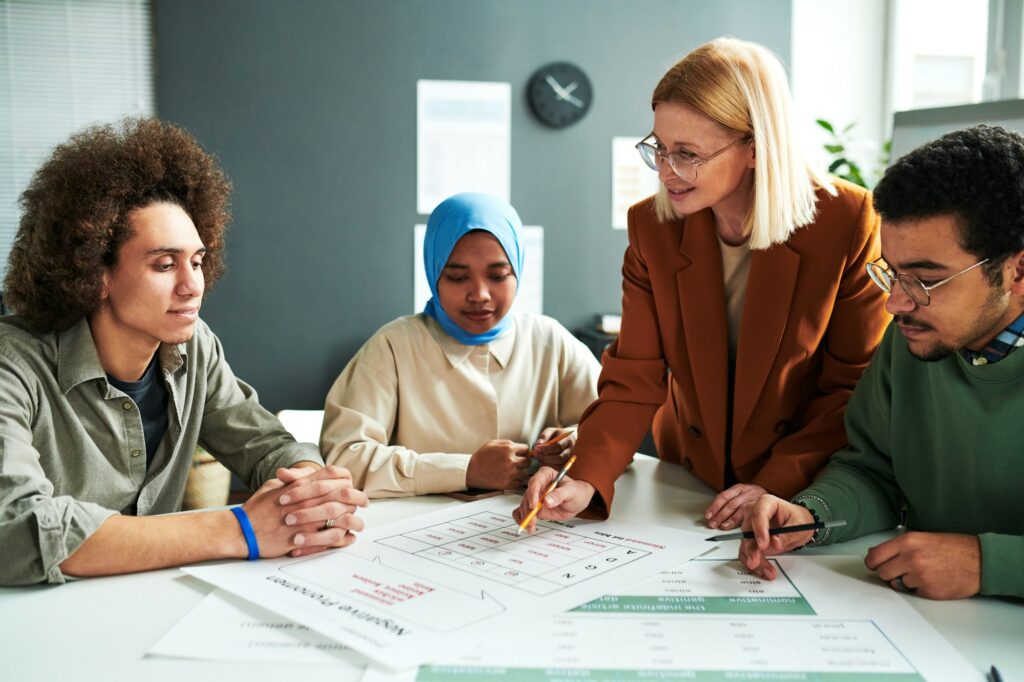 Confident teacher in eyeglasses explaining information in document